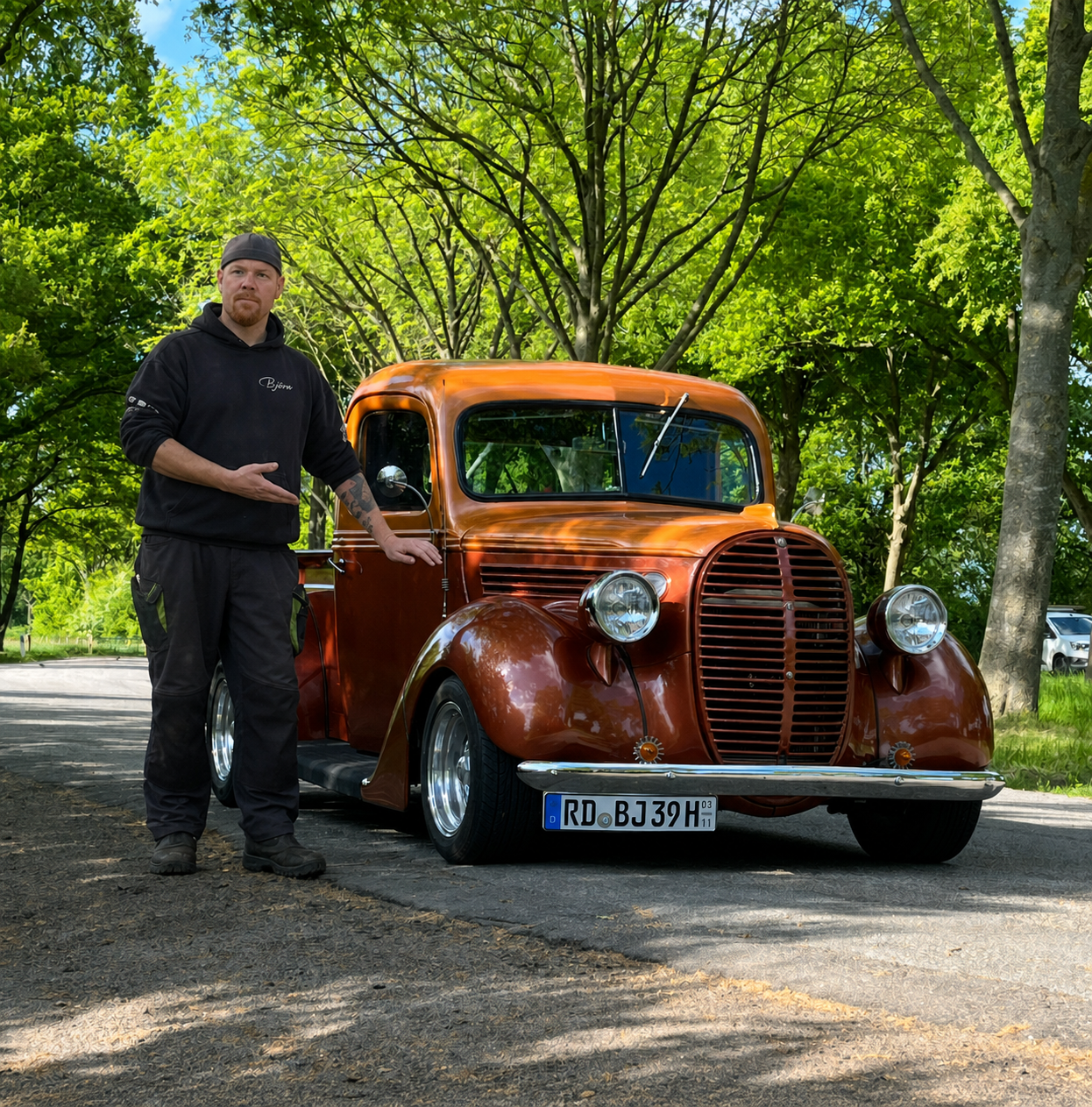Björn Börner steht neben einem kupferfarbenen amerikanischen Oldtimer-Pickup und präsentiert das Fahrzeug